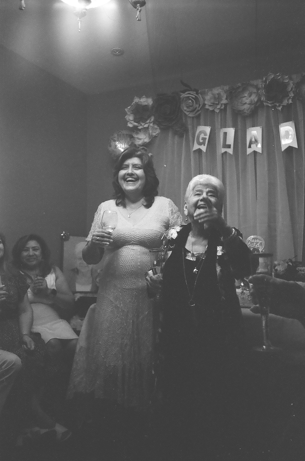 Two women laughing together at a family party, in black and white